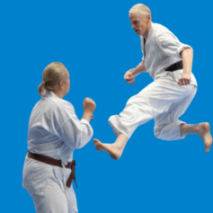 Två människor i vita karatedräkter och svarta bälten övar på karate. Den andra är ryggen mot kameran och har sina knytnäv framför ansiktet medan den andra har hoppat i luften och har sträckt ut sitt andra ben mot sin motståndare.