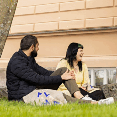 two people sitting on grass, laugning