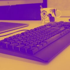 banner duotone Lila-gulfärgad bild på ett tangentbord, en datormus och en kaffemugg