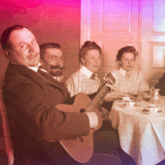 SLS Gammalt foto på glada människor som sitter vid ett kaffebord och en av dem spelar gitarr.